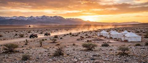 Camp de luxe dans le désert d'Agafay près de Marrakech au coucher du soleil, avec des quads et les montagnes de l'Atlas à l'horizon