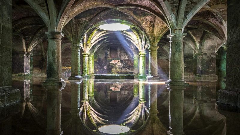 Intérieur de la citerne portugaise d'El Jadida, au Maroc : arches et colonnes en pierre reflétées dans l'eau peu profonde