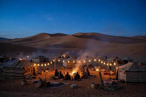 Rassemblement musical dans le désert du Sahara au crépuscule : musiciens autour d'un feu, lanternes et tentes berbères sous les dunes